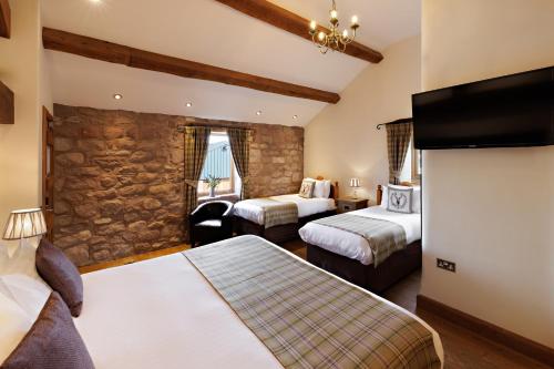 a hotel room with two beds and a flat screen tv at Heaton House Farm in Macclesfield