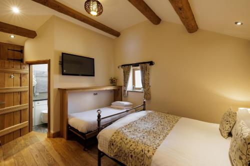 a bedroom with two beds and a flat screen tv at Heaton House Farm in Macclesfield