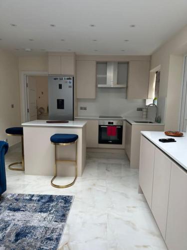 een keuken met witte kasten en een blauwe kruk bij CozyCorner - 2 Bed in Egham Heathrow Windsor in Egham