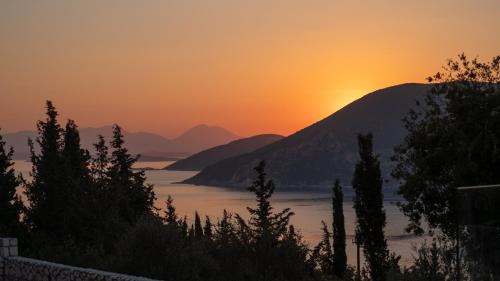 a sunset over a body of water with mountains at Fiscardo Sunny Villas in Fiskardho