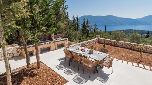 a table and chairs on a patio with a view of the water at Fiscardo Sunny Villas in Fiskardho