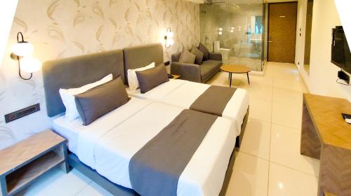 a bedroom with a large bed and a living room at Hotel Nova Bizz in Rajkot
