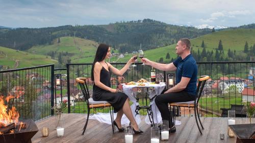a man and woman sitting at a table drinking wine at Stara Pravda Hotel - Vykrutasy in Bukovel