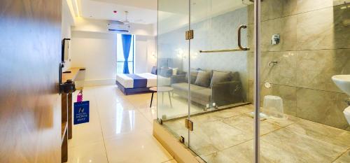 a bathroom with a glass shower with a couch in it at Hotel Nova Bizz in Rajkot