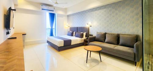 a bedroom with a bed and a couch and a table at Hotel Nova Bizz in Rajkot
