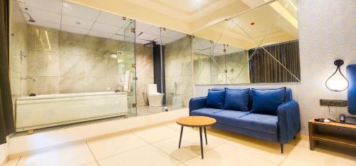 a living room with a blue couch and a shower at Hotel Nova Bizz in Rajkot