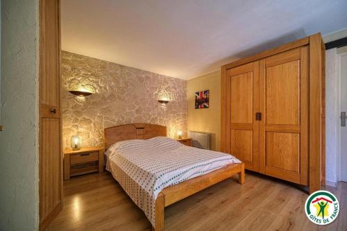 a bedroom with a bed and a wooden cabinet at Les Platanes in Tulette