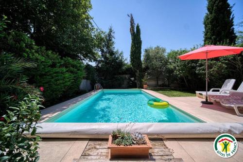 a swimming pool in a yard with an umbrella at Les Platanes in Tulette