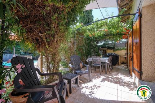 a patio with chairs and a table and vines at Les Platanes in Tulette