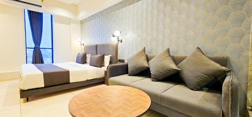 a bedroom with a couch and a bed and a table at Hotel Nova Bizz in Rajkot