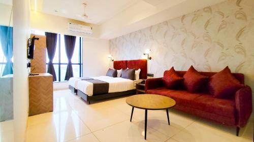 a hotel room with a bed and a red couch at Hotel Nova Bizz in Rajkot