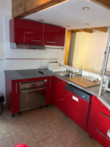une cuisine avec des armoires rouges et un évier dans l'établissement Petite maison quartier hist, à Collioure
