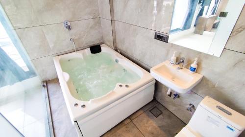 a bathroom with a bath tub and a sink at Hotel Nova Bizz in Rajkot