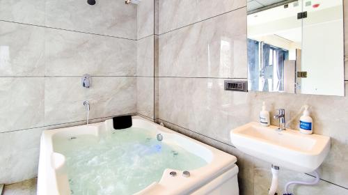 a bathroom with a bath tub and a sink at Hotel Nova Bizz in Rajkot