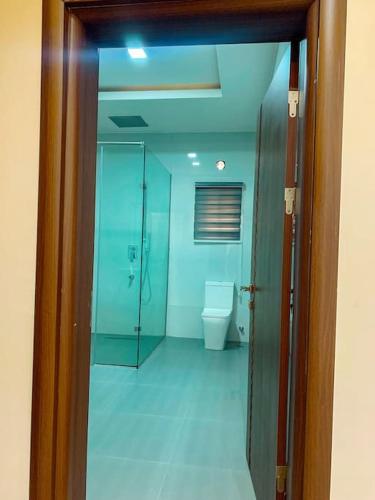 a bathroom with a toilet and a glass doorway at Sha'an Residence in Garki