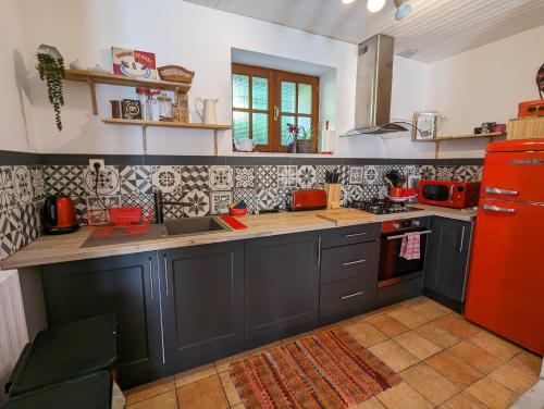 a kitchen with black cabinets and a red refrigerator at Chez Betty in Saint-Germain-de-Confolens