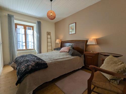 a bedroom with a bed and a chair and a window at Chez Betty in Saint-Germain-de-Confolens