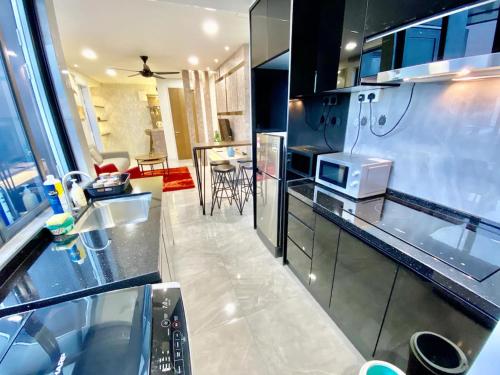 a kitchen with stainless steel appliances and a living room at Imperio Residence Melaka in Melaka