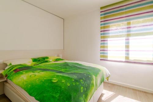 - une chambre avec une couverture verte sur un lit et une fenêtre dans l'établissement Piso reformado a pie de playa Sa Riera Begur, à Begur