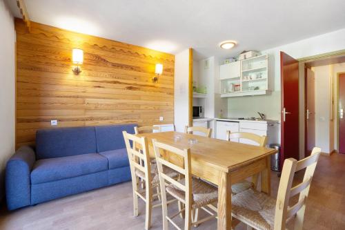 - une salle à manger avec un canapé bleu, une table et des chaises dans l'établissement A1 308 Appart au pied des pistes, à Saint-François-Longchamp