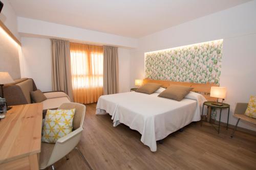 a bedroom with a white bed and a painting on the wall at Hotel Yola in Altafulla