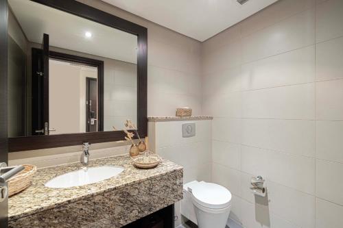 a bathroom with a sink and a toilet and a mirror at Luxury Apartments in Anantara Resort with Stunning Burj AlArab & Sea Views in Dubai