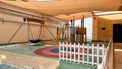 a playground in a building with a fence and swings at Luxury Apartments in Anantara Resort with Stunning Burj AlArab & Sea Views in Dubai