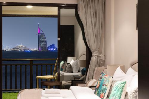 a hotel room with a balcony with a view of the city at Luxury Apartments in Anantara Resort with Stunning Burj AlArab & Sea Views in Dubai
