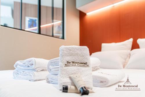 a pile of towels and towels on a bed at De Montescal - SPA Tub and AC Cosy apartment a prime location 40m2 in Paris