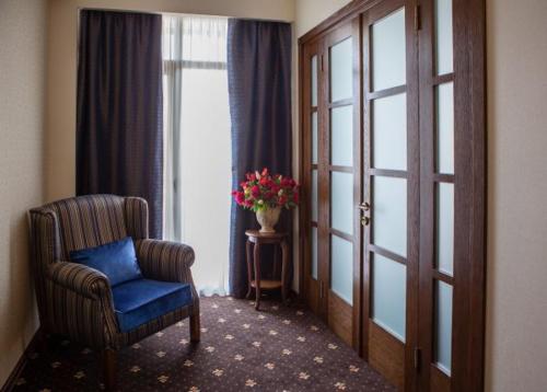 a room with a chair and a window with a vase of flowers at Tbilisi Laerton Hotel in Tbilisi City