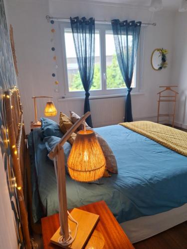 une chambre avec un lit avec des draps bleus et une fenêtre dans l'établissement Le soleil Dunkerquois, à Dunkerque