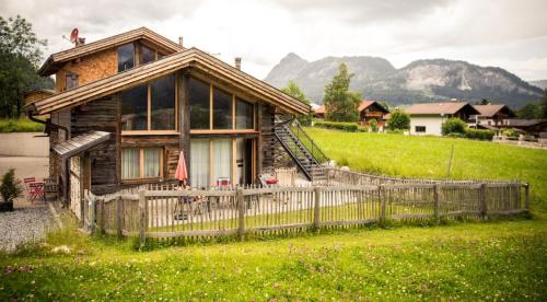 a wooden house with a fence in front of it at Braito's Seaside Lodges und Suites, Ferienhäuser und Ferienwohnungen in Haldensee