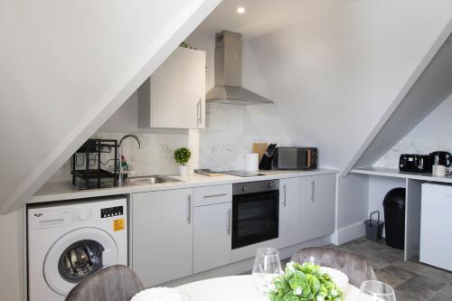 a kitchen with white cabinets and a washer and dryer at Open Mind Property - Cosy Apartment with 2 Beds in Portsmouth