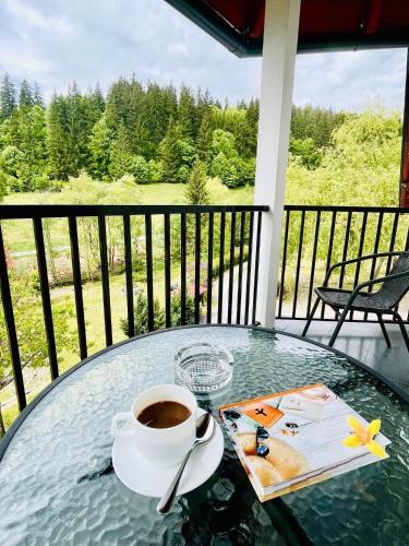 a cup of coffee sitting on a glass table on a balcony at Cabana Transylwonder in Sicasău