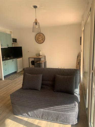 un salon avec un canapé et une horloge au mur dans l'établissement Petit cocon dans le 8 ème, à Marseille