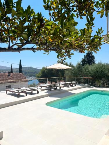 a swimming pool with picnic tables and an umbrella at seaview apartment - villa a’more in Milna