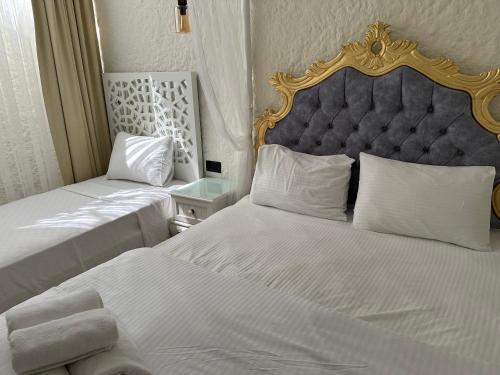 a bedroom with two beds with white sheets and a blue headboard at Grand Alaçatı Butik Hotel in Alacati