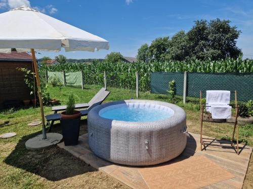 a hot tub in a yard with an umbrella at DRiM Wood House - no party house in Lasinja
