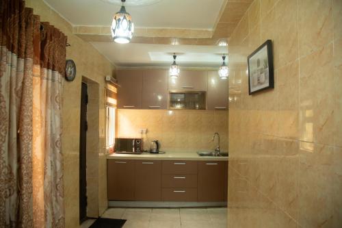 a kitchen with brown cabinets and a sink at Home Away from Home - Gowon Estate near Gemade, Ipaja, Lagos in Lagos