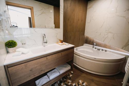 a bathroom with a tub and a sink and a tub and a toilet at Хотел Панорама in Pleven