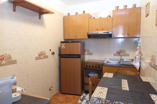 a kitchen with a refrigerator and a table in it at Sotto La Rocca - Casa vacanze a 5 minuti dal mare in Cefalù