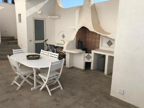 a white dining room with a table and chairs at Villa Al Mare Guest House in Tre Fontane