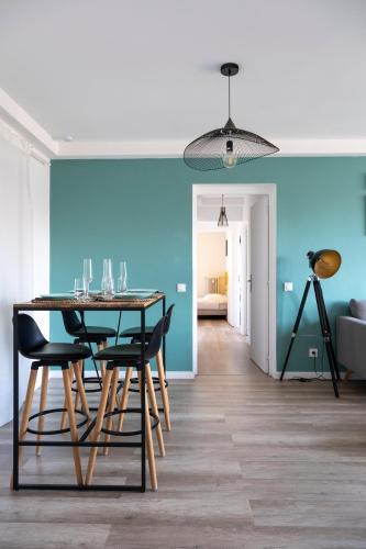 une salle à manger avec une table, des chaises et un mur bleu dans l'établissement Appartement cosy et raffiné proche gare Toulon, à Toulon