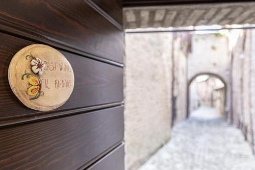 un panneau en bois sur le côté du bâtiment dans l'établissement IL RIFUGIO casa vacanze centro storico confortevole posto auto, à Nocera Umbra