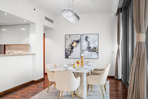 a dining room with a table and white chairs at Luxury 4BR Flat, Downtown Dubai, Pool, Gym, PS5, Sleeps 11 Guests in Dubai