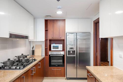 a kitchen with stainless steel appliances and wooden cabinets at Luxury 4BR Flat, Downtown Dubai, Pool, Gym, PS5, Sleeps 11 Guests in Dubai