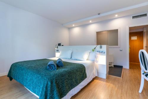 a bedroom with a large bed with a green blanket at ARTIEM Audax - Adults Only in Cala Galdana