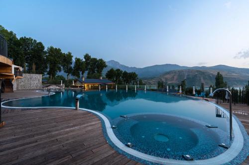 a large swimming pool with a wooden deck and mountains at Burchmulla Resorts in Burchmulla