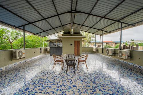 ロナバラにあるAlaya Stays - Imperial Mystara 5BHK near Khandala Hillsのタイルフロアのパティオ(テーブル、椅子付)