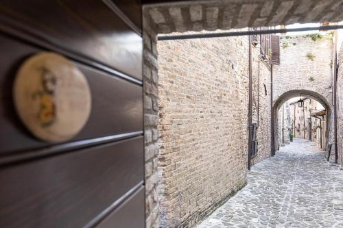 Une allée avec une horloge sur le côté d'un bâtiment dans l'établissement IL RIFUGIO casa vacanze centro storico confortevole posto auto, à Nocera Umbra